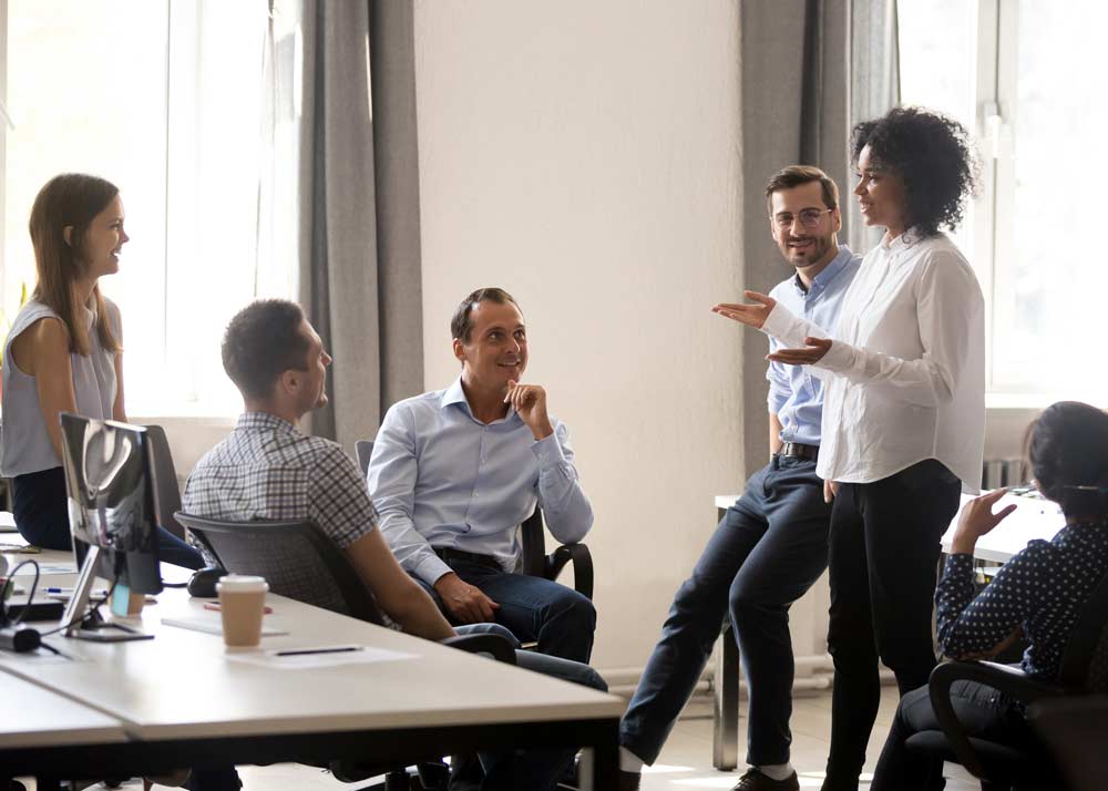 group of workers talking at office desks