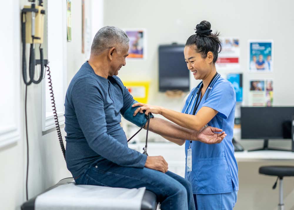 older man having blood pressure taken by medical staff